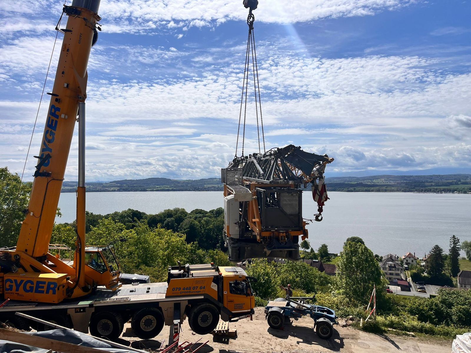 Grue mobile soulevant une grue à tour démontée, le lac en arrière-plan